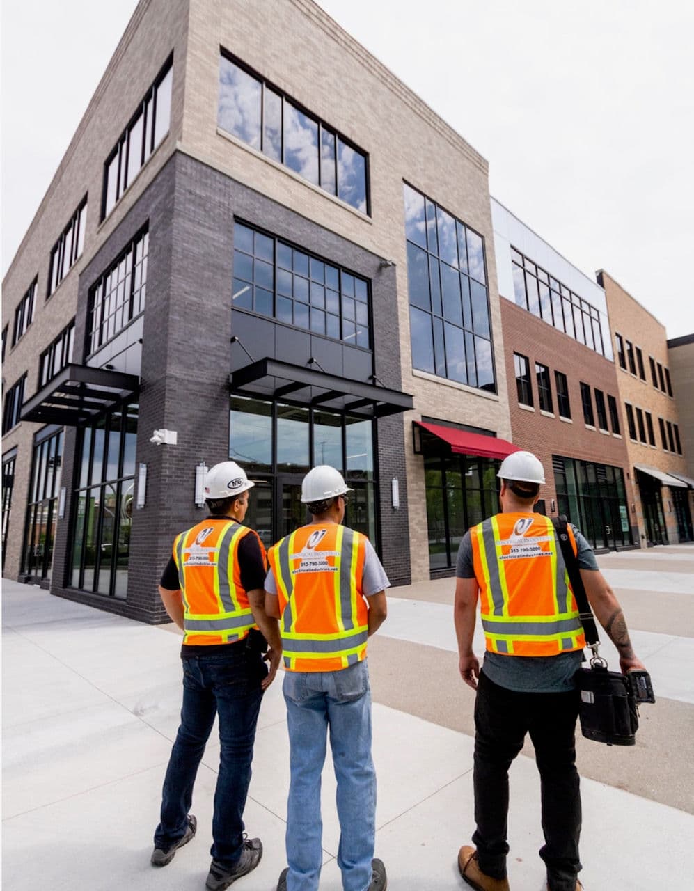 Construction workers in safety vests assess a building under construction.