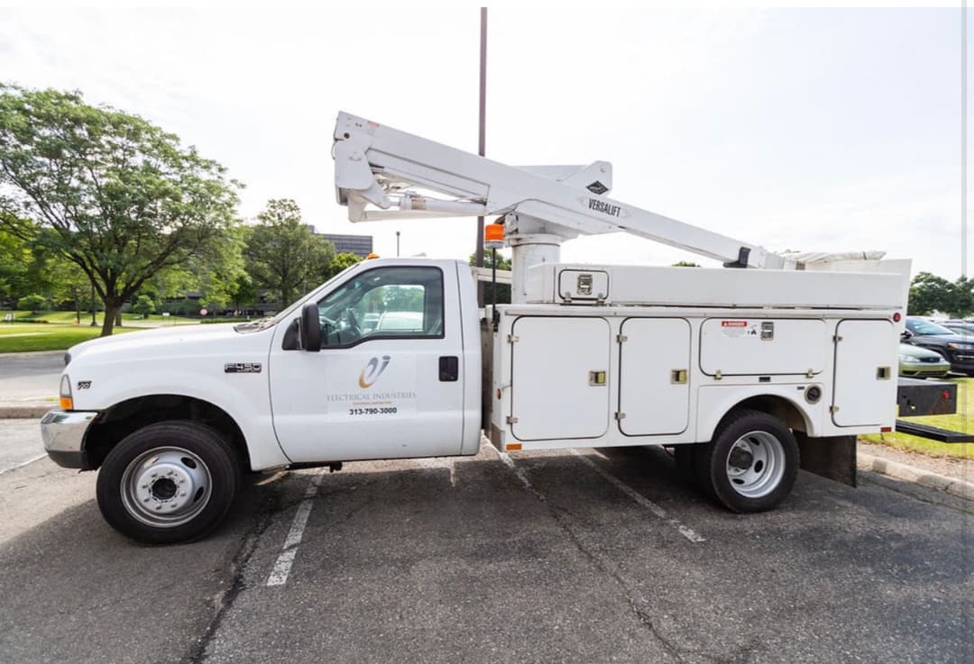 White bucket truck parked in a lot, featuring the logo of an electrical services company.